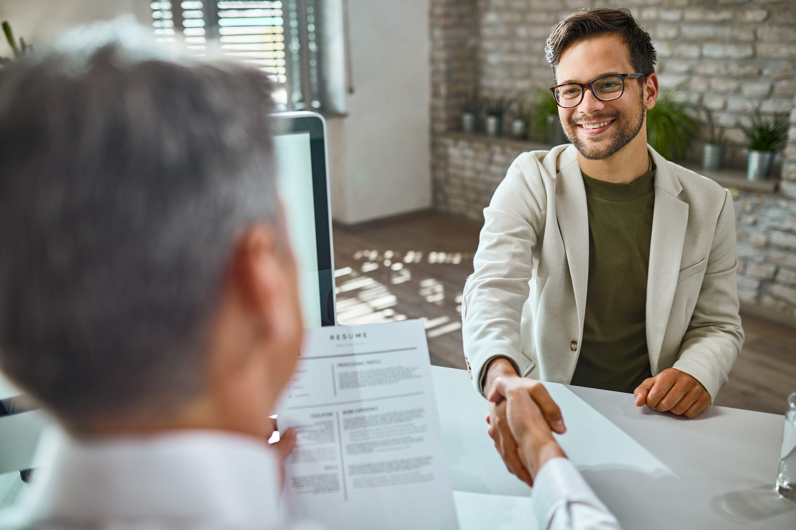 Candidato contento en entrevista de trabajo en inglés con entrevistador revisando CV